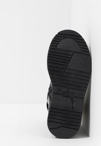 Černá podrážka sportovní obuvi s texturovaným gripem, vyrobená z gumového materiálu, s hlubokými žebry, mírným zakřivením u špičky a označením velikosti "28".