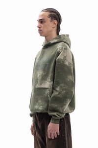 Olivově zelená mikina s kapucí se strukturovaným povrchem a světle skvrnitým vzorem. Má přední kapsu a kapuci pro větší teplo.