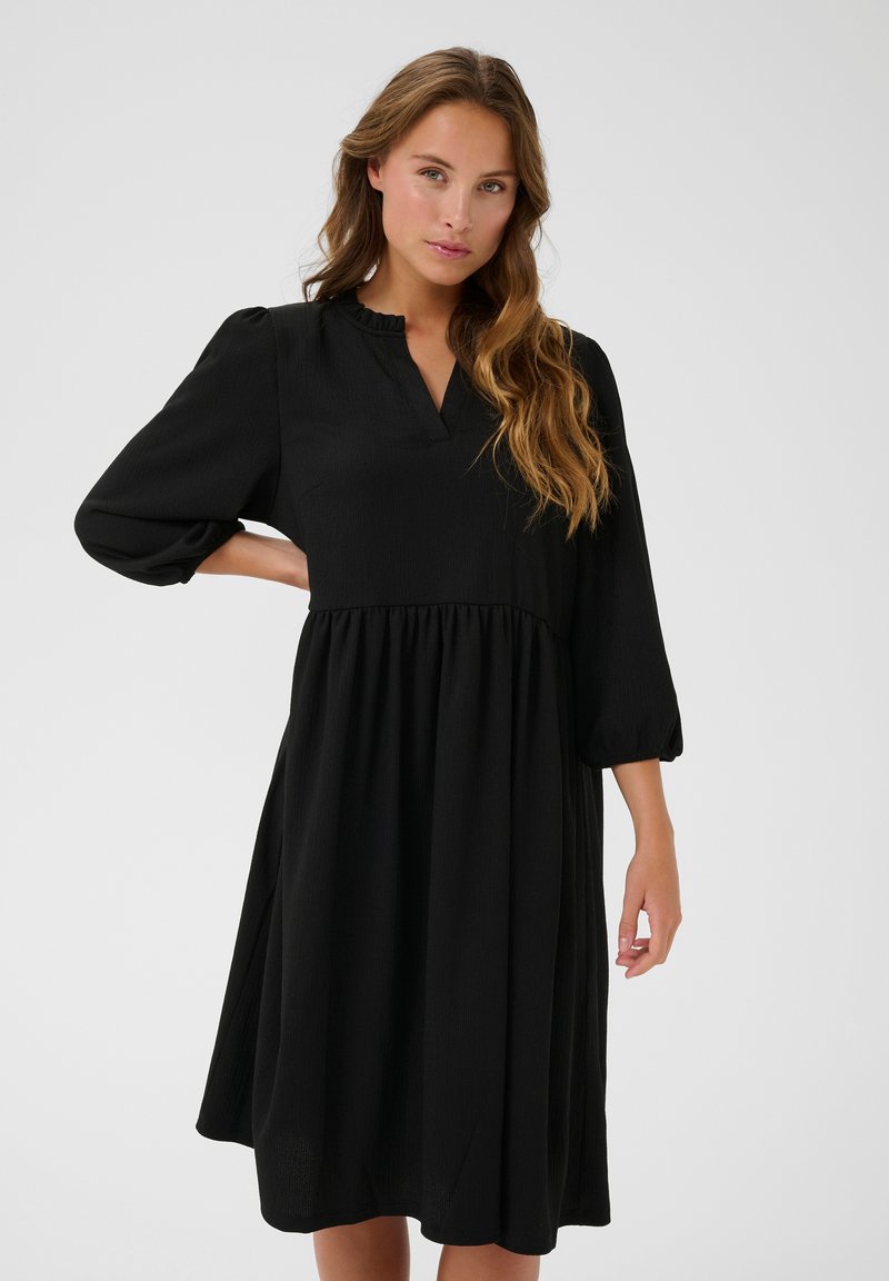 Black dress with a V-neck and ruffled collar, three-quarter puffed sleeves, and a flared skirt. Made from textured fabric.
