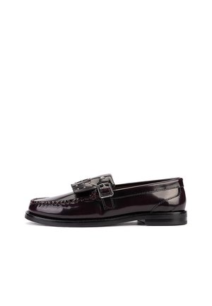 Mocasín de cuero burdeos oscuro con hebilla decorativa y detalles de flecos en la parte superior, tacón bajo negro y bordes cosidos.