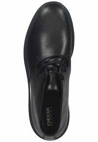 Chaussure en cuir noir avec une finition lisse, bout rond et fermeture à lacets. Comprend une semelle intérieure rembourrée et un design minimaliste.