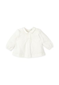 Camisa blanca de manga larga con cuello y cierre de botones, y fondo redondeado. Tejido suave con una textura sutil, que presenta un pequeño detalle bordado en la parte inferior.