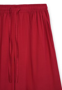 Pantaloni rossi con vita elastica realizzati in un tessuto morbido e leggero. Presentano un cordoncino e una vestibilità rilassata con pieghe laterali.