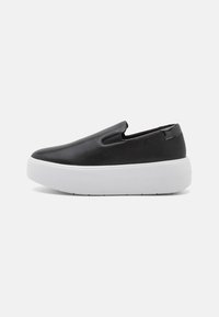 Černé slip-on boty s hladkým koženým svrškem, bílou platformou a bočními výřezy pro snadné obouvání. Minimalistický design bez viditelného kování.
