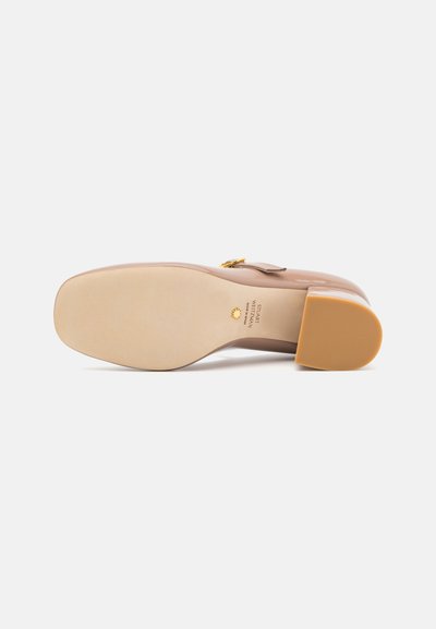 Chaussure à talons nus avec un bout carré, dessus en cuir lisse, accent en métal doré, et semelle texturée en caoutchouc marron clair.