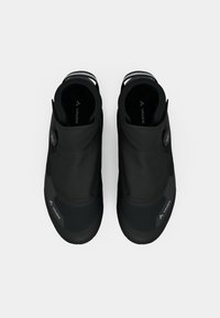 Sapatos pretos à prova d'água com um cabedal flexível, detalhes texturizados e um sistema de fecho seguro, apresentando um logotipo em relevo na lateral.