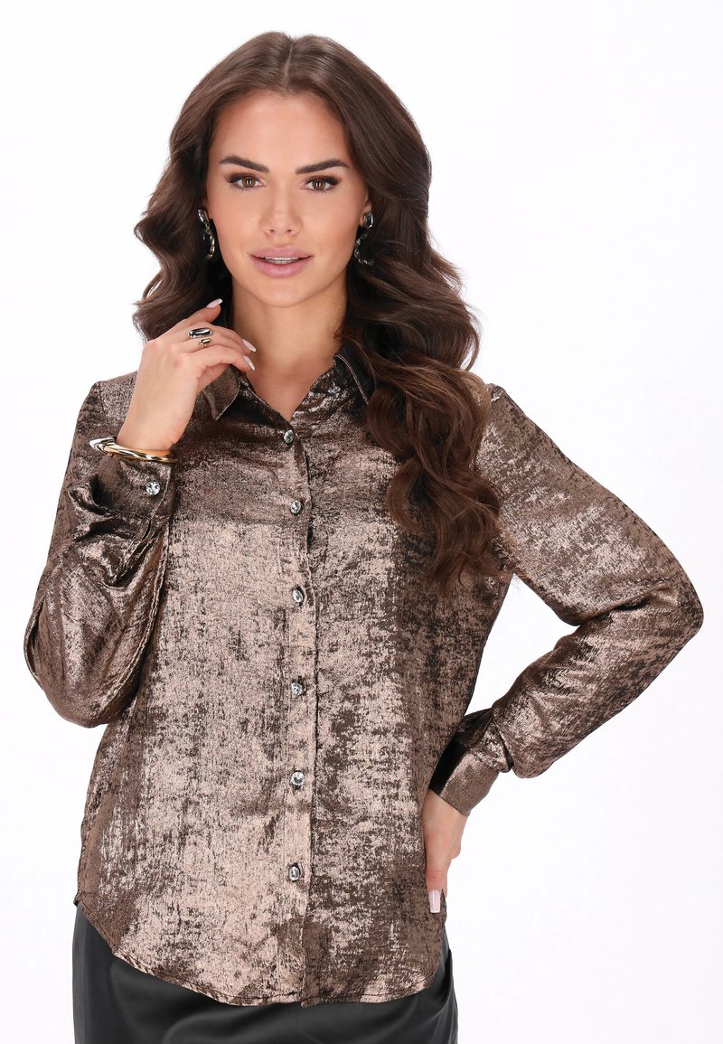 Metallinhohtoinen pronssinvärinen nappipaita, jossa on teksturoitu pinta, pitkät hihat ja kiiltävät napit, yhdistettynä mustiin alaosaan.