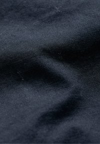 Tejido oscuro y texturizado con un suave brillo. Presenta arrugas sutiles y patrones finamente tejidos, creando profundidad e interés visual.