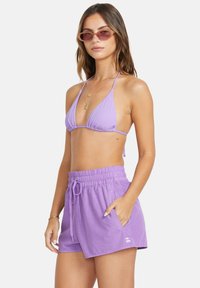 Lila Bikini mit dreieckigen Cups und passenden lila Kordelzug-Shorts. Weicher Stoff mit elastischem Bund und Seitentaschen.