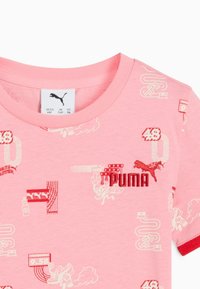 Rozā kokvilnas krekls ar apaļu apkakli, kas rotāts ar baltu grafiku un sarkanu izšūtu "PUMA" tekstu un logotipu.