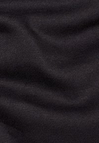 Tessuto a maglia nero con una texture liscia, caratterizzato da cuciture fini e uniformi e una caduta morbida. Nessun motivo o accento particolare.