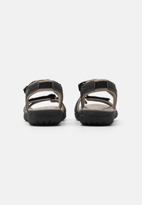 Svarta och beige öppna sandaler med justerbar rem, texturerad gummisula och mjuk fotbädd för komfort. Förstärkta sömddetaljer.