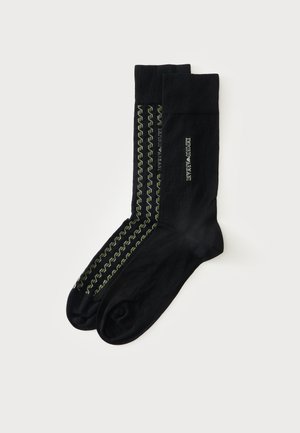 Mustad põlveni sukad, üks Emporio Armani logoga, teine rohelise ja valge kettmustri ning logotekstiga.