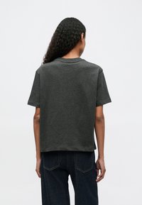 Dark gray cotton t-shirt with short sleeves, crew neckline, and a relaxed fit. Features a smooth texture and simple design.