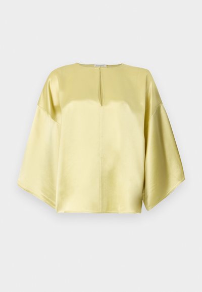 Blusa de satén amarilla con cuello redondo, mangas cortas y anchas, y un detalle de ojal en el frente. Textura suave y corte relajado.