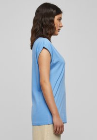 Svetlomodré tričko s krátkym rukávom vyrobené z jemnej látky, s voľným strihom, okrúhlym výstrihom a detailmi s rolled sleeve hem.