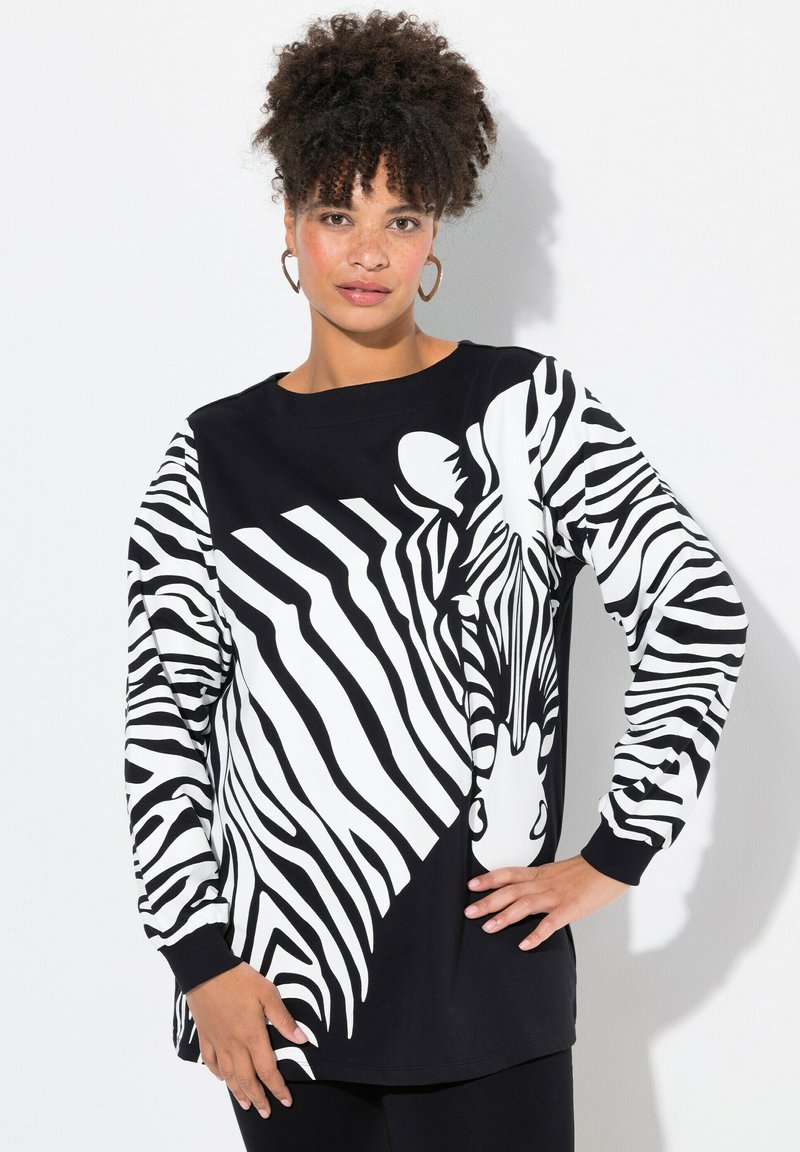Maglietta a maniche lunghe in bianco e nero con una grande grafica di una zebra, maniche a righe di colore contrastante e scollatura arrotondata.