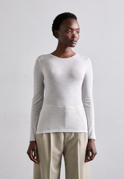 Haut à manches longues gris clair en texture ribdée douce avec un col arrondi, associé à un pantalon beige ample taille haute.