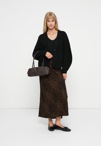 Musta neulecardigan nappikiinnityksellä, yhdistetty leopardikuosisena maksihameeseen. Asusteina tumma ruskea käsilaukku ja mustat tasapohjaiset kengät.