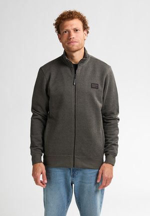 Donkergrijze ritsvest met een gestructureerde afwerking, voorzien van een staande kraag, zijzakken en een klein logopatch op de borst.