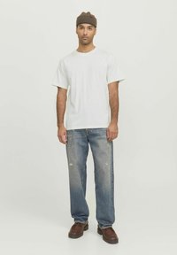 White short-sleeve t-shirt, faded blue straight-leg jeans with distressed detailing, brown knit beanie, brown lace-up shoes.