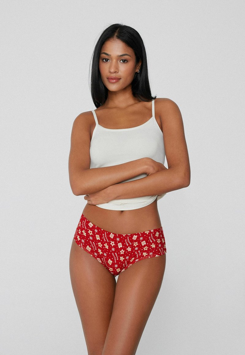 Red patterned underwear with various white motifs, paired with a fitted white tank top. The fabric appears soft and stretchy.