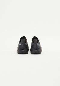 Chaussures de sport noires avec une tige texturée, semelle rembourrée et logo bleu contrastant. Présente un talon arrondi et un design minimaliste.