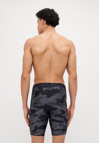 Schwarz gemusterte Kompressionsshorts mit glatter Textur und elastischem Bund, entworfen für Komfort und Unterstützung während des aktiven Tragens.