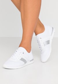 Vita stickade sneakers med silverglitterrand, snörning, rund tå, elastisk ankelskärp och texturerad sula.