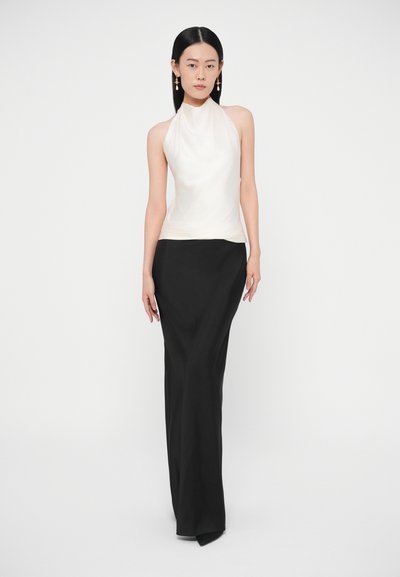 Τοπ με halterneck από κρεμ μετάξι, συνδυασμένο με μαύρη φούστα μήκους μέχρι το πάτωμα. Λείο ύφασμα, εφαρμοστή γραμμή, με ελαφριά ουρά στο τελείωμα.
