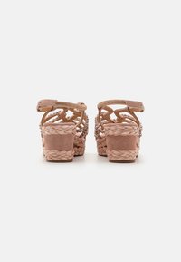 Rosa semskede sandaler med en flettet plattform, med et vevd stropp bak og dekorative detaljer. Åpen og luftig design.