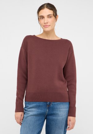 Burgundy knitted sweater with a boat neckline, ribbed cuffs, and bottom hem. Worn over light blue denim jeans.