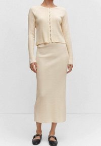 Kermanvärinen, resorakenteinen neulejakku, jossa napitettu edusta, yhdistetty samansävyiseen midihameeseen. Rakenteinen kangas, pitkät hihat, istuva siluetti.