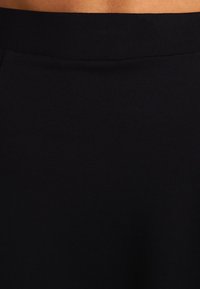 Czarna spódnica z gładkiego, elastycznego materiału z wysokim stanem. Projekt jest prosty, bez widocznych wzorów czy metalowych elementów.