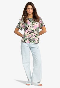 Korte mouwen bloemen top met een roze en groene botanische print; gecombineerd met lichtblauwe wijde jeans. Gladde stoftextuur, casual ontwerp.