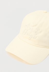 Casquette de baseball jaune clair avec un motif floral brodé et le texte "Hugo", en tissu lisse, dotée d'une visière incurvée et de détails de couture.