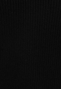 Svart ribbat tyg med en texturerad yta, som har vertikala linjer från stickmönstret, enhetlig färg och inga synliga mönster eller accenter.