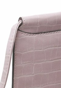 Lys pink faux krokodillet læder håndtaske med en glat tekstur, buet top og en tynd skulderrem. Har pæne sting og en subtil glans.