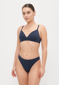 Mornarsko modri bikini set z trikotno modrčko in visokim pasom. Gladka tekstura, nastavljive naramnice, minimalistična zasnova, brez vidnih vzorcev.