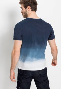 T-shirt a maniche corte, blu navy, con una sfumatura gradiente dal blu scuro al bianco. Tessuto morbido con una vestibilità comoda e scollo rotondo.