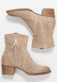 Beżowe zamszowe botki na kostkę z blokowym obcasem, zamkiem błyskawicznym z boku i dekoracyjnym plecionym detalem z tyłu. Gładka tekstura, klasyczny design.