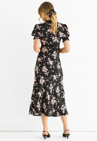 Black floral dress with short puff sleeves, featuring a fitted bodice and flowing skirt. Accented with pink flowers and lace detailing.