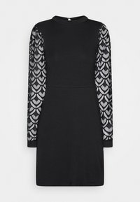 Robe noire avec de longues manches en dentelle transparente ornées d'un motif en forme de cœur, col haut et silhouette ajustée, fabriquée dans un matériau lisse et extensible.