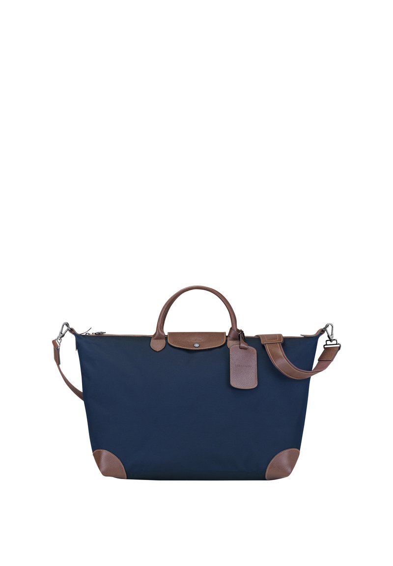 Marineblaue Stoff-Tote-Bag mit braunen Lederakzenten, abgerundeten Griffen, einem abnehmbaren Schulterriemen und einem Gepäckanhänger-Detail.