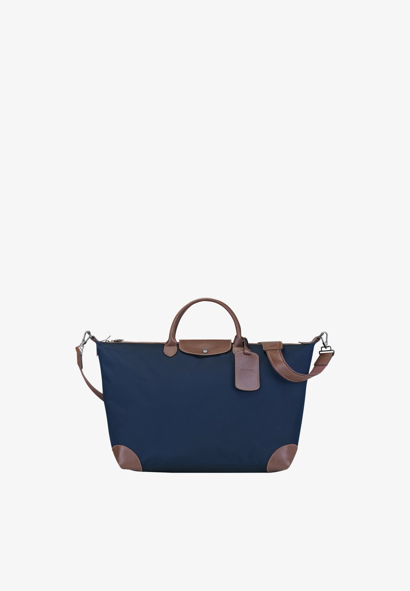 Marineblaue Stoff-Tote-Bag mit braunen Lederakzenten, abgerundeten Griffen, einem abnehmbaren Schulterriemen und einem Gepäckanhänger-Detail.