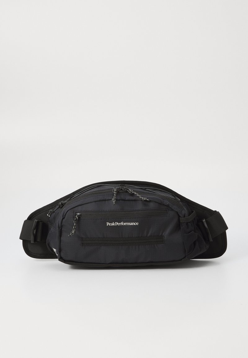 Čierna bedrová taška vyrobená z nylonu s viacerými zipsovými vreckami a nastaviteľným popruhom. Na prednej strane obsahuje logo "PeakPerformance".