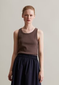 Braunes ärmelloses, geripptes Oberteil mit rundem Ausschnitt, kombiniert mit einem Rock mit elastischem Taillenbund in Marineblau. Einfaches Design, glatte Textur, lässige Passform.