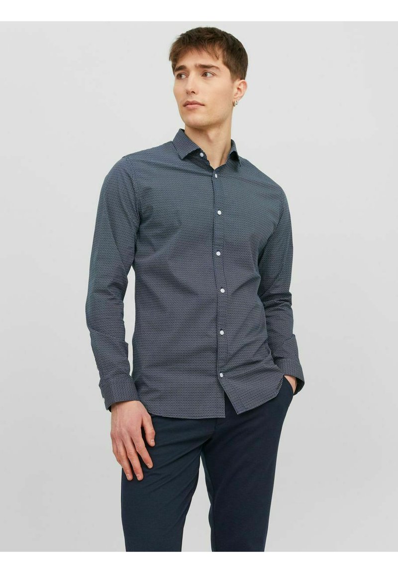 Camicetta abbottonata di colore blu navy con un motivo geometrico, maniche lunghe e colletto classico, realizzata in tessuto testurizzato. Adatta per un look casual.