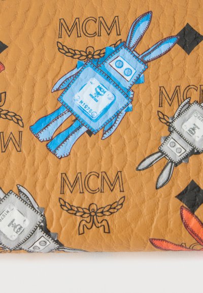 Δερμάτινη επιφάνεια με μοτίβο από στυλιζαρισμένα ρομποτικά κουνέλια σε μπλε, γκρι και πορτοκαλί, συνοδευόμενα από λογότυπα MCM και στεφάνια δάφνης σε ταμπά φόντο.