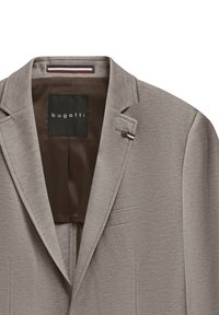 Helle beige Blazer aus strukturiertem Stoff, mit Reverskragen und einer einzelnen Knopfverschluss. Das Innere ist mit einem dunkelbraunen Futter und einem Etikett ausgestattet.